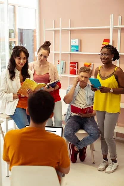 A teacher empathetically listening to a student in a colorful classroom, with other students engaged in group activities in the soft-focused background, symbolizing social-emotional support.