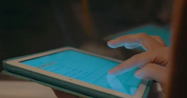 A close-up of a hand pointing to a digital compliance checklist on a tablet, with various software icons representing data management and security in the background.