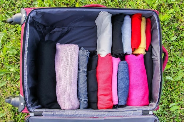 A neatly organized open suitcase with a few versatile clothing items rolled and folded, demonstrating a capsule wardrobe.