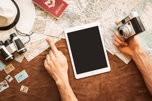 A person meticulously planning their travel itinerary on a tablet, surrounded by travel guides and coffee. The scene suggests detailed strategizing and organization.