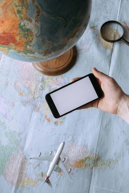 A person's hand holding a smartphone with a travel booking app open, showing flight and hotel options, a world map in the background.