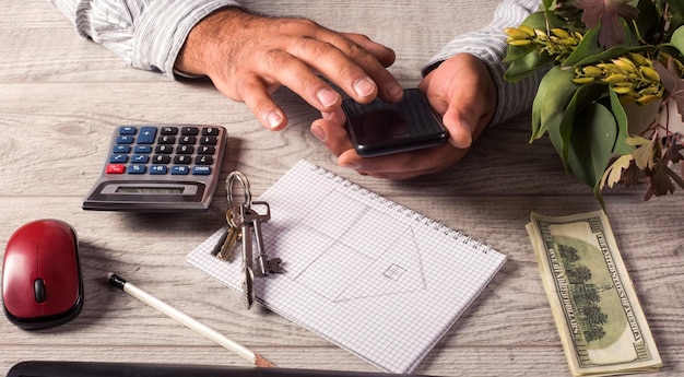 A close-up of a hand using a calculator to figure out mortgage payments, with charts and graphs in the background indicating financial planning and debt-to-income ratios.