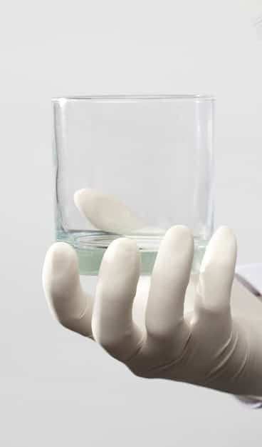A close-up of a scientist's hand adjusting a component in a clean, brightly lit laboratory, with blurred background elements suggesting advanced renewable energy research equipment, symbolizing innovation and scientific progress.