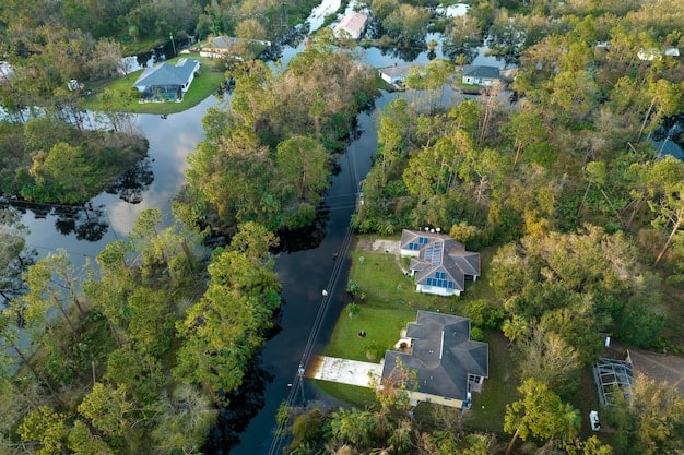 Aerial view of a flooded suburban neighborhood after a hurricane, illustrating widespread inland freshwater flooding, with emergency vehicles visible.