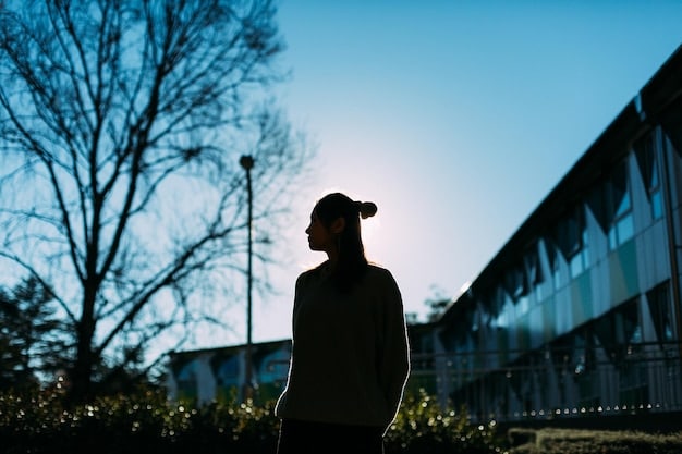 A determined student staring at a clear sky with a college campus silhouette in the background, holding a textbook that glows with digital light, symbolizing aspirations and future success after test preparation.